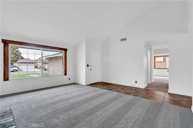 tiled empty room with high vaulted ceiling, baseboards, visible vents, and carpet flooring