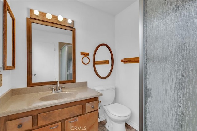 bathroom with toilet, a shower with door, and vanity