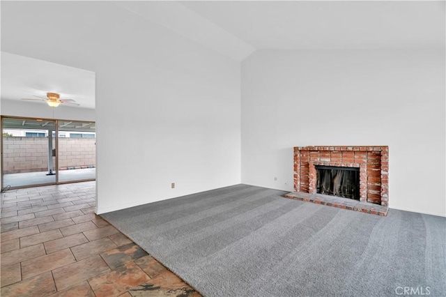 unfurnished living room featuring a ceiling fan, a brick fireplace, vaulted ceiling, and carpet floors