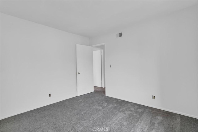 unfurnished room with visible vents and dark carpet