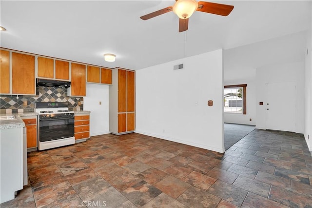 kitchen with visible vents, light countertops, decorative backsplash, gas range, and under cabinet range hood