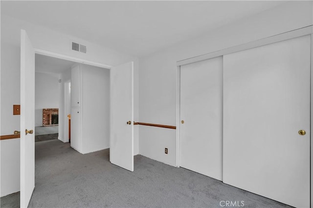 unfurnished bedroom with a closet, visible vents, a fireplace, and carpet flooring