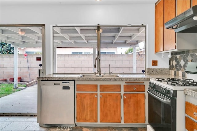 kitchen featuring under cabinet range hood, a sink, decorative backsplash, brown cabinetry, and gas range