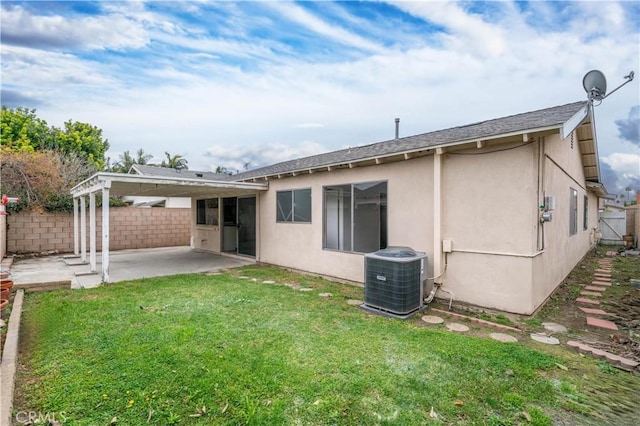 rear view of property featuring cooling unit, fence, a lawn, stucco siding, and a patio area