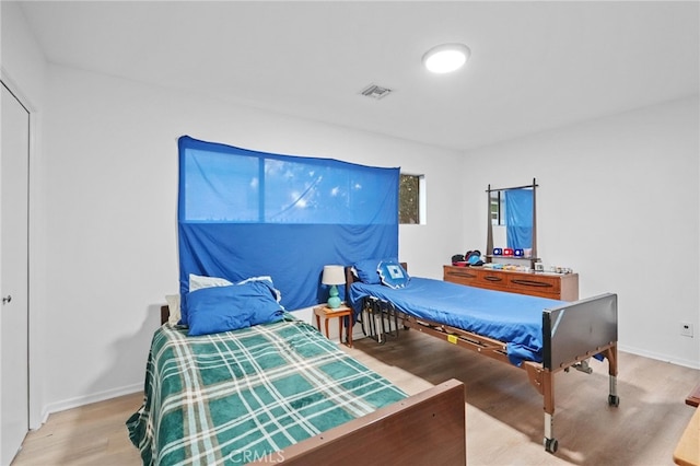 bedroom featuring visible vents, baseboards, and wood finished floors