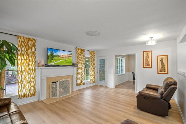 living room featuring light wood-type flooring and a fireplace with raised hearth