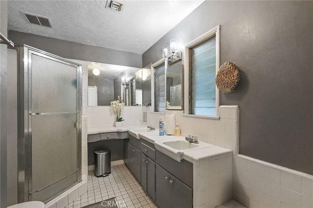 bathroom with visible vents, a textured ceiling, and a stall shower