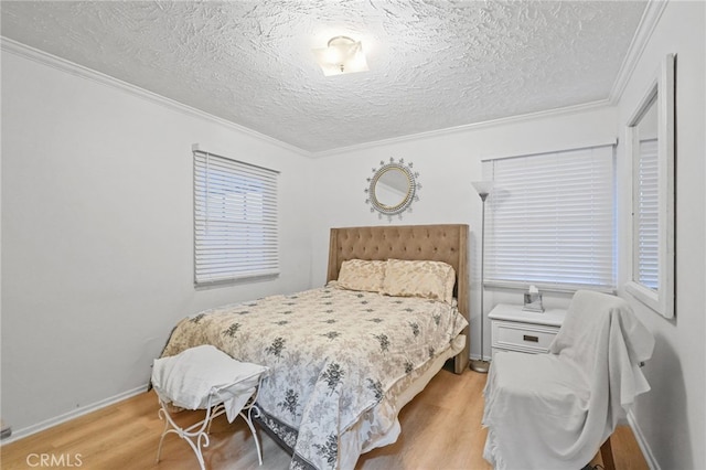 bedroom with baseboards, a textured ceiling, light wood-style flooring, and crown molding