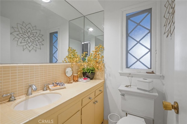 bathroom featuring vanity, toilet, and tasteful backsplash