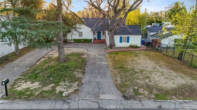 view of front facade with stucco siding, driveway, and fence