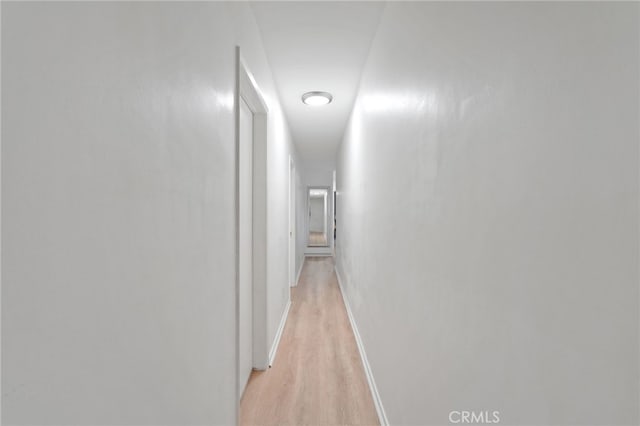 hall with light wood-style flooring and baseboards