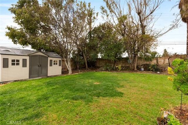 view of yard featuring an outbuilding, a fenced backyard, and a shed