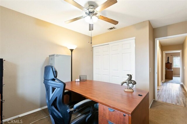 office space with ceiling fan, carpet floors, visible vents, and baseboards