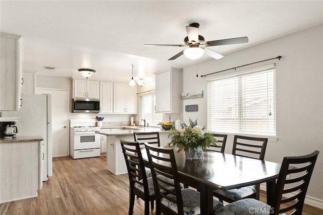 dining area with light wood-type flooring, ceiling fan, and baseboards