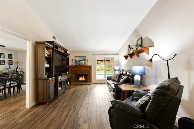 living room with lofted ceiling, a brick fireplace, baseboards, and wood finished floors