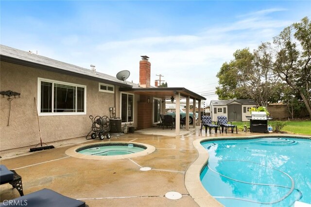 pool with an outbuilding, a hot tub, area for grilling, a patio area, and a shed