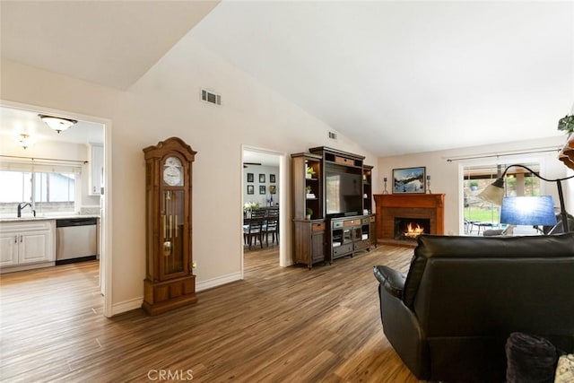 living room with light wood-style floors, a brick fireplace, and a healthy amount of sunlight