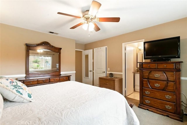 carpeted bedroom with a ceiling fan, visible vents, and ensuite bath