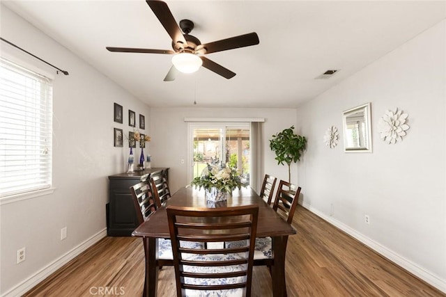 dining room with light wood finished floors, baseboards, visible vents, and a ceiling fan