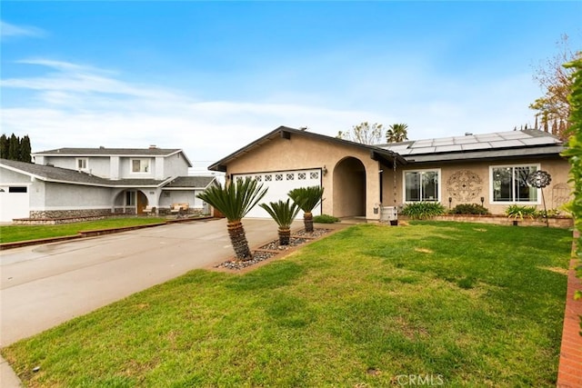 ranch-style home with driveway, an attached garage, roof mounted solar panels, a front lawn, and stucco siding