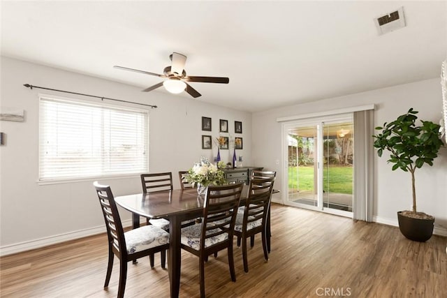 dining space with ceiling fan, wood finished floors, visible vents, and baseboards