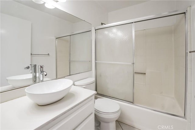 bathroom with vanity, toilet, and combined bath / shower with glass door