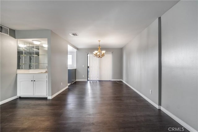 interior space with a notable chandelier, baseboards, dark wood-type flooring, and visible vents