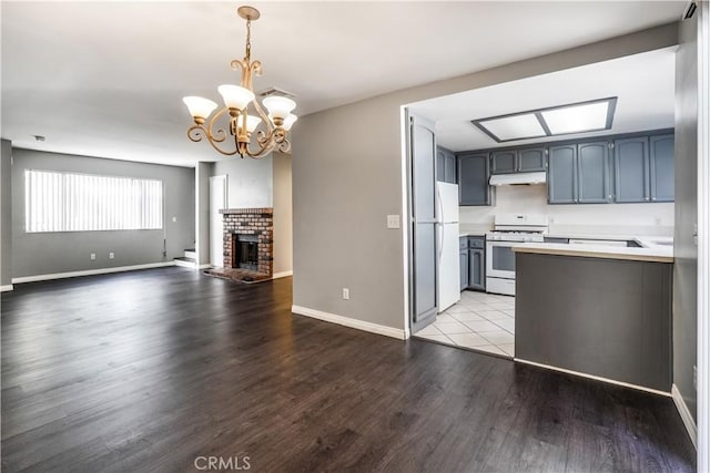 kitchen with under cabinet range hood, open floor plan, wood finished floors, white appliances, and light countertops