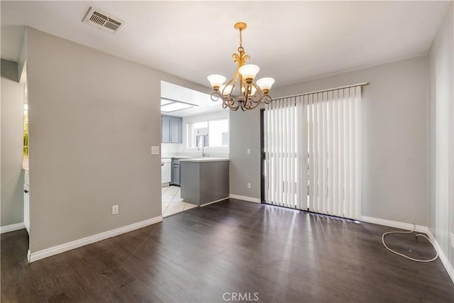 unfurnished dining area featuring baseboards, wood finished floors, visible vents, and a chandelier