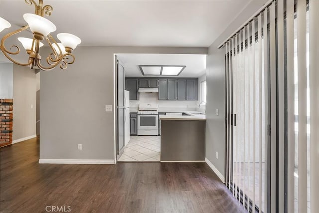 kitchen with light countertops, an inviting chandelier, wood finished floors, white appliances, and a sink