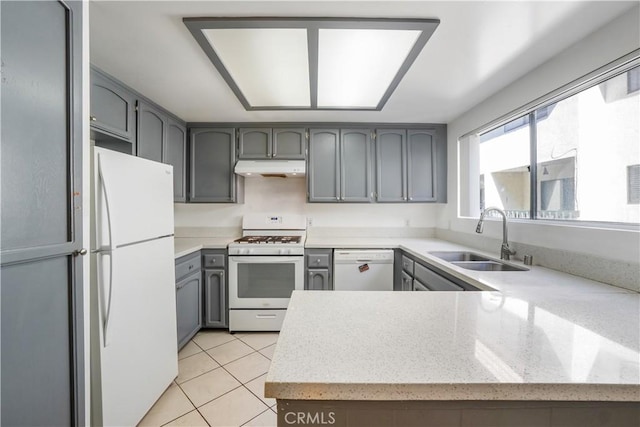 kitchen featuring a sink, under cabinet range hood, white appliances, light tile patterned floors, and light stone countertops