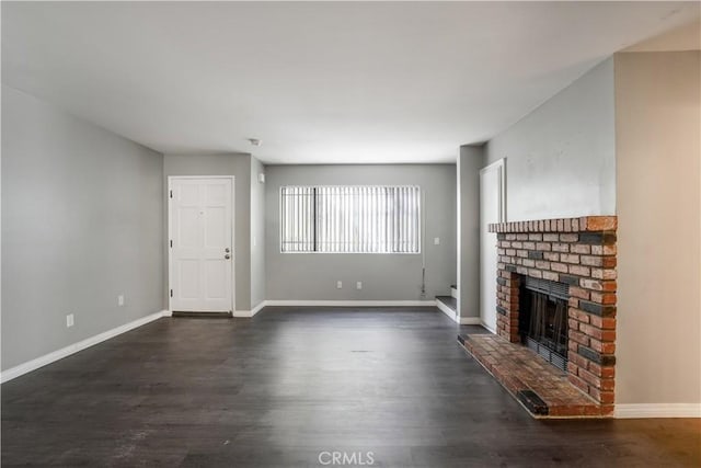 unfurnished living room with a fireplace, baseboards, and dark wood-style flooring