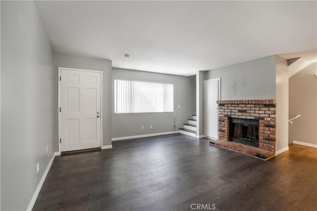 unfurnished living room with a fireplace, stairs, dark wood-type flooring, and baseboards