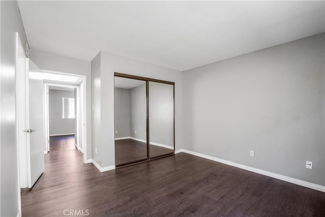 unfurnished bedroom with a closet, baseboards, and wood finished floors