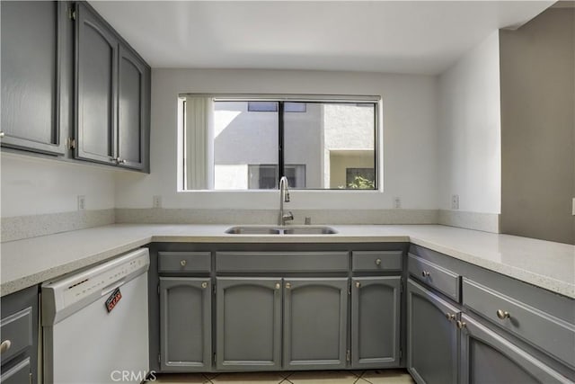 kitchen featuring gray cabinets, dishwasher, light countertops, and a sink