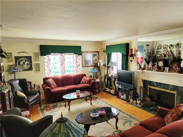 living area with a premium fireplace, wood finished floors, and crown molding