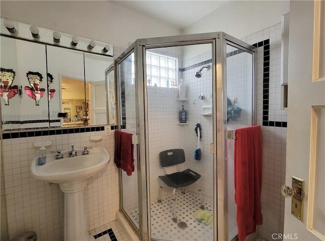 bathroom with a shower stall, vaulted ceiling, and tile walls