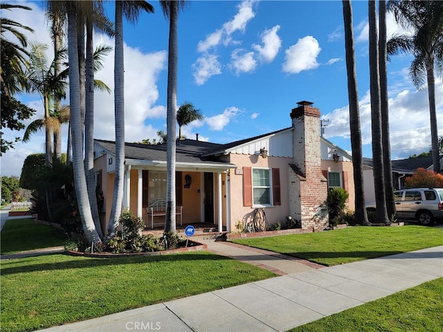 view of front facade with a front lawn, a chimney, and stucco siding