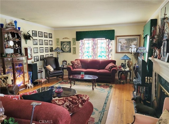 living area featuring visible vents, ornamental molding, a fireplace, and hardwood / wood-style flooring