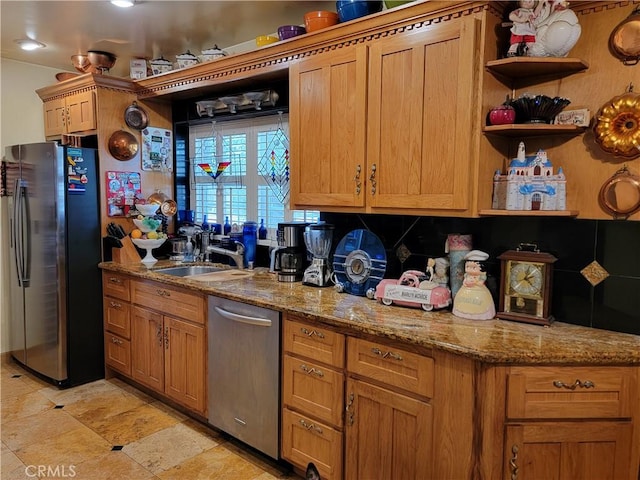 kitchen featuring tasteful backsplash, appliances with stainless steel finishes, a sink, and light stone countertops