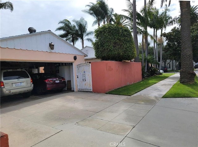 view of side of property featuring driveway and a gate