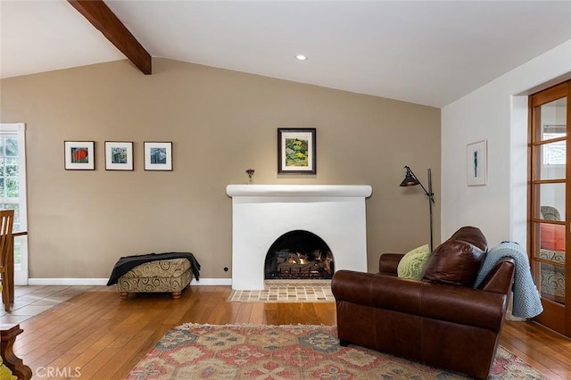 living area featuring vaulted ceiling with beams, hardwood / wood-style floors, a wealth of natural light, and baseboards