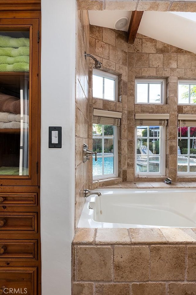 full bathroom featuring lofted ceiling with beams and tiled tub