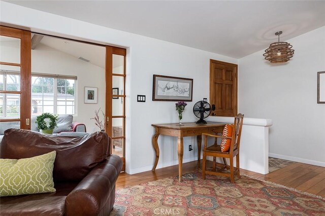 interior space featuring visible vents, baseboards, vaulted ceiling, and wood finished floors