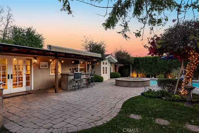 view of patio / terrace featuring outdoor dry bar, french doors, and an outdoor hot tub