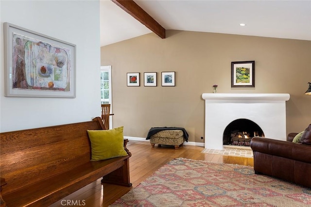 living room featuring vaulted ceiling with beams, a fireplace with flush hearth, hardwood / wood-style flooring, and baseboards