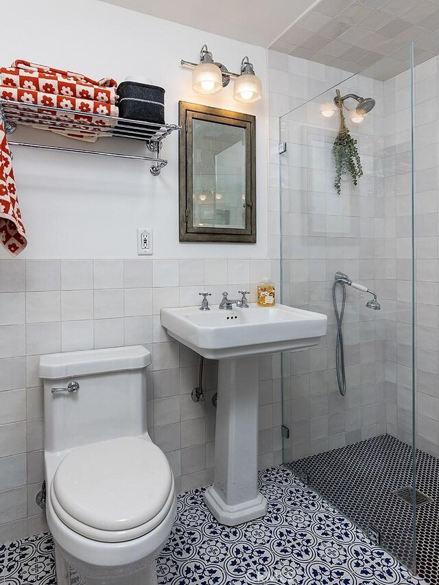 full bath featuring tile patterned flooring, toilet, tile walls, and a shower stall