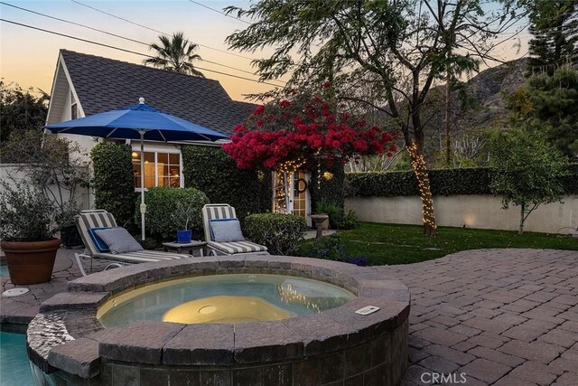 view of patio featuring fence and an in ground hot tub