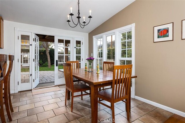 tiled dining room with lofted ceiling, an inviting chandelier, baseboards, and a wealth of natural light