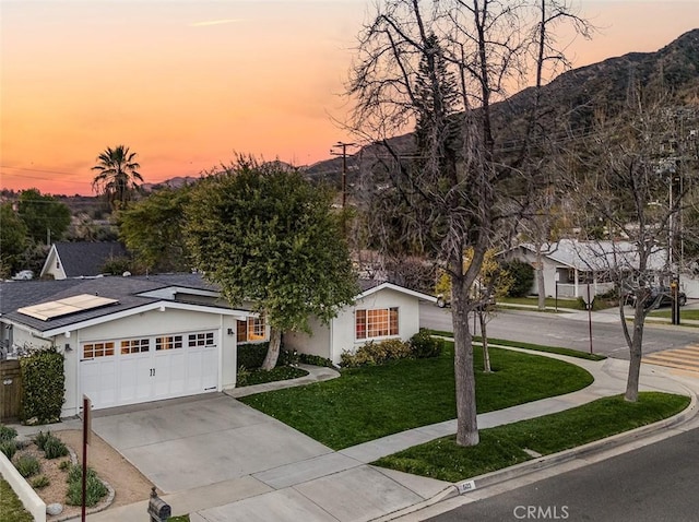 single story home with a garage, driveway, a yard, a mountain view, and stucco siding